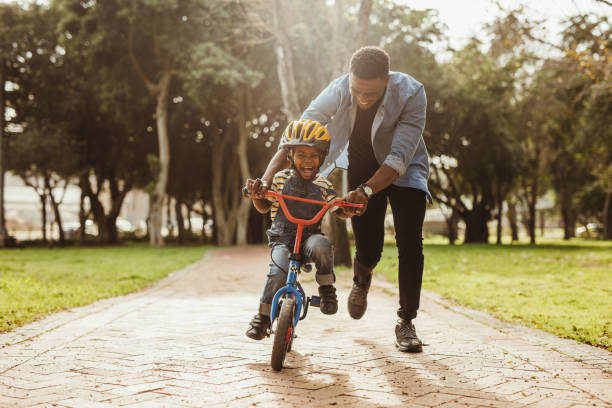 père qui apprend à son fils à faire du vélo